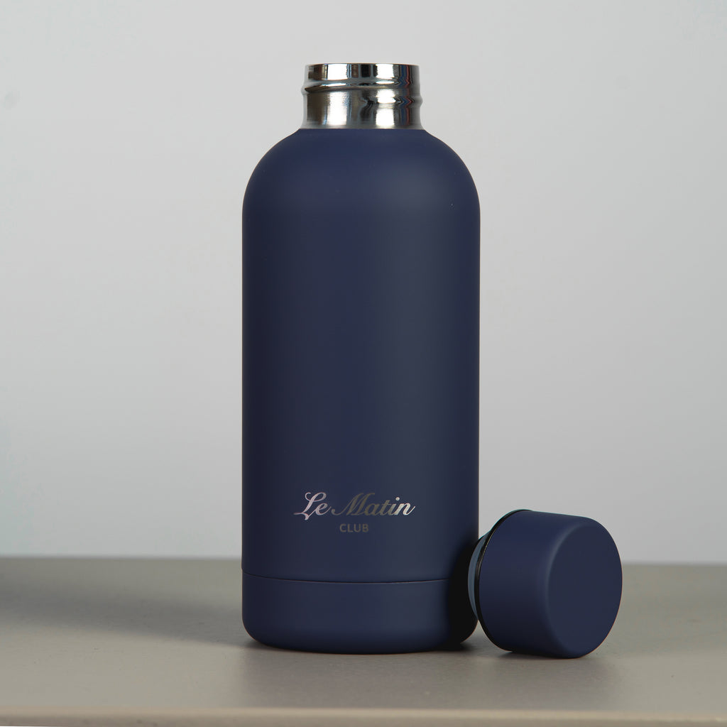 Navy blue water bottle with silver cap on a light gray background