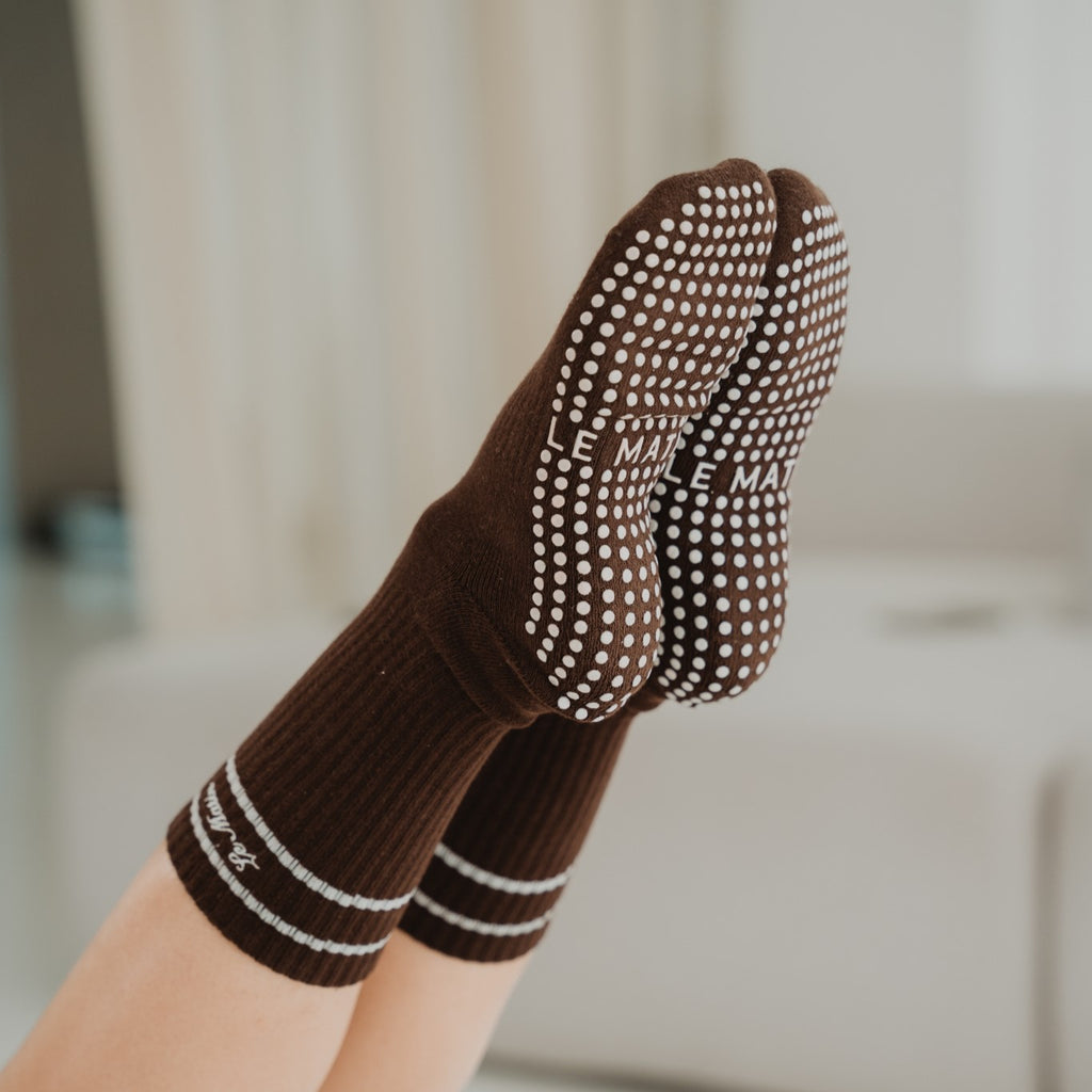 Brown socks with grey pattern worn by a person on a blurred indoor background