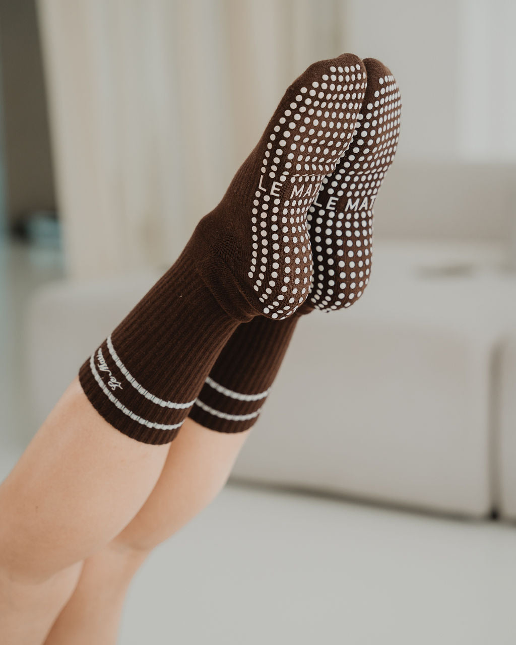 Brown socks with grey pattern worn by a person on a blurred indoor background