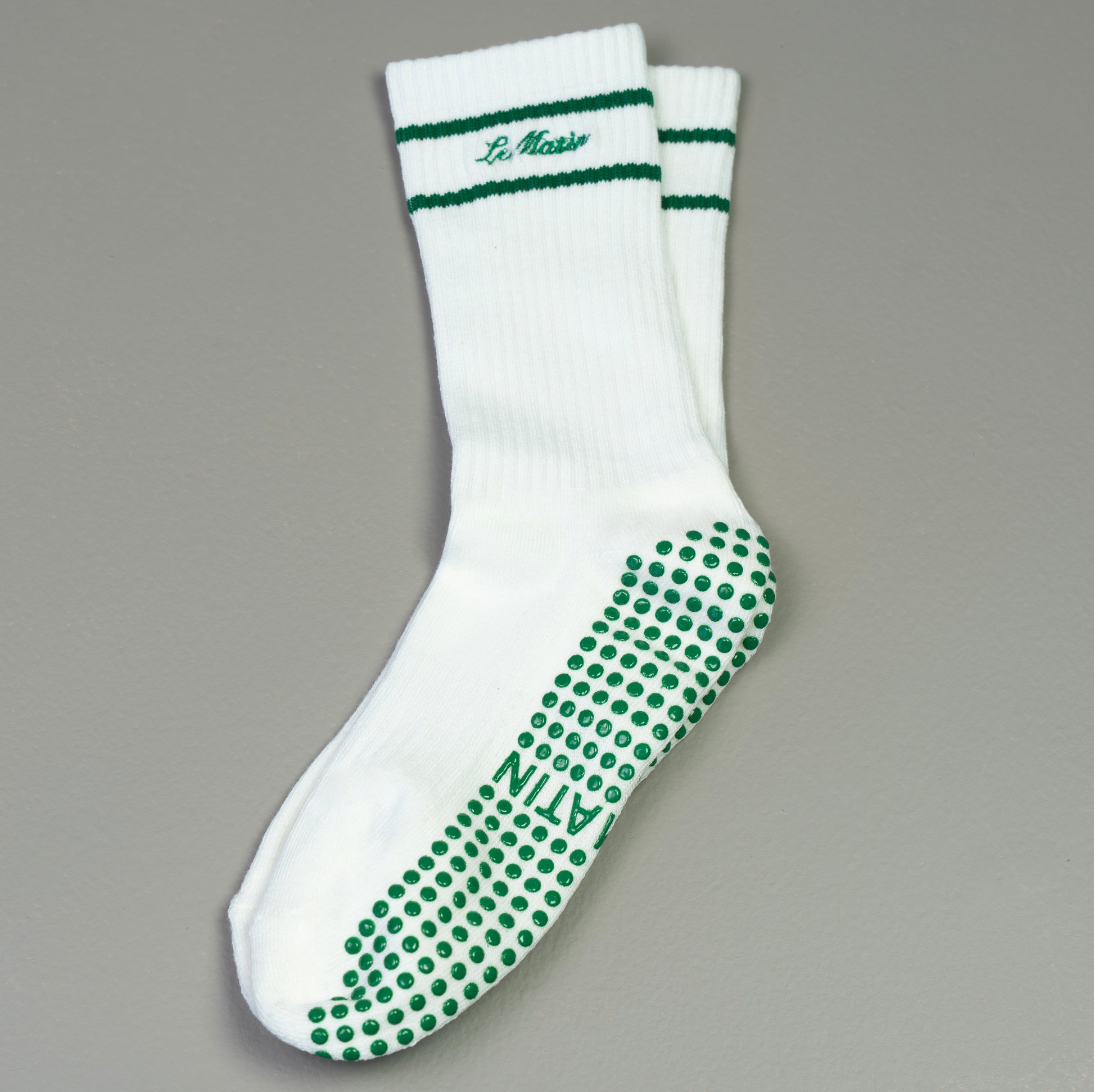 White sock with green accents and Le Matin logo embroided text  on a gray background