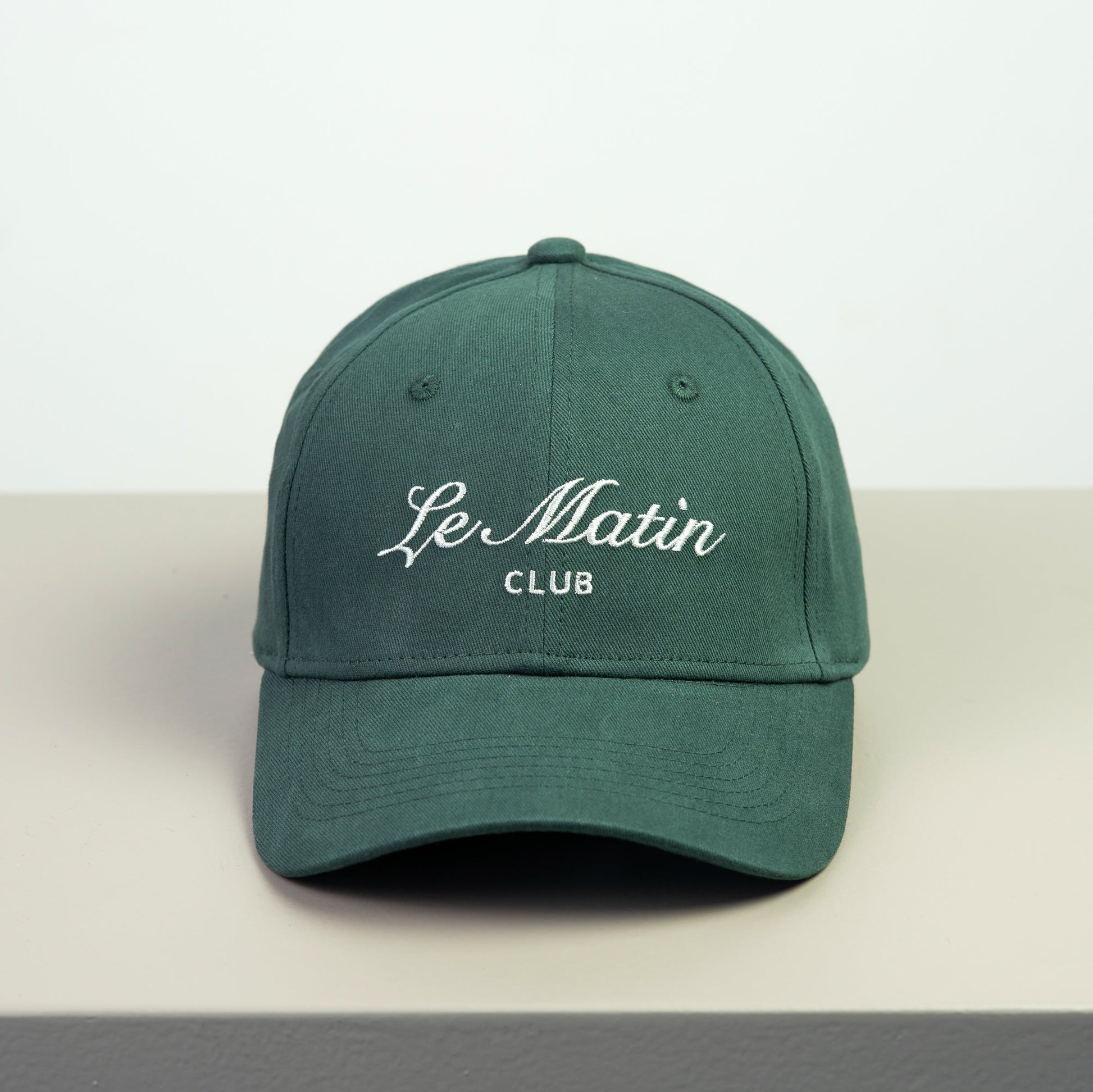 Green cap with 'Le Matin Club' embroided text on a white background
