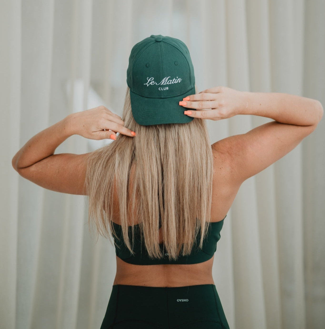 Person wearing a green Le Matin cap and sports outfit against a neutral background