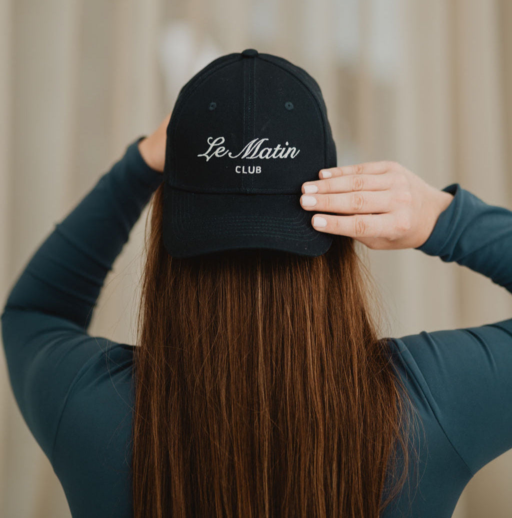 Girl wearing a navy cap with 'Le Matin Club' text against a neutral background