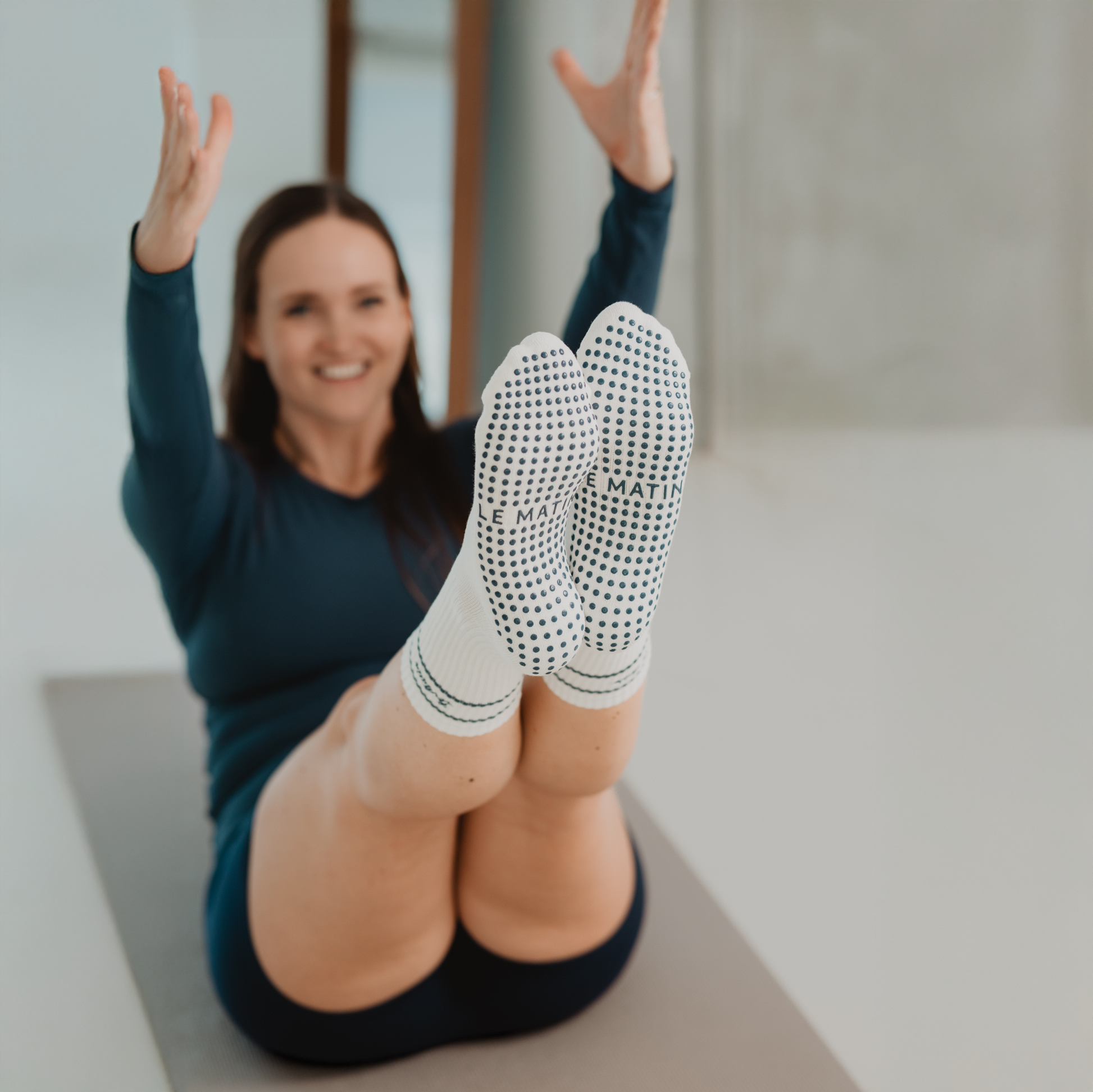 Person wearing white socks with navy patterns, sitting on a yoga mat indoors.