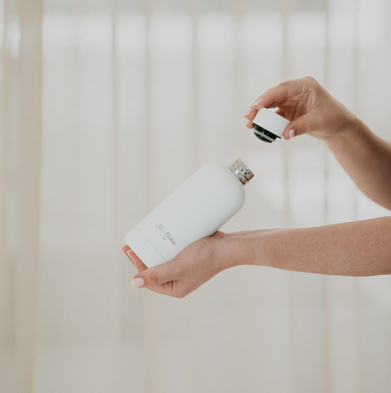 White water bottle.Person holding a white water bottle with a blurred background